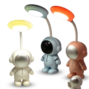 Tres lámparas de escritorio LED con forma de astronauta en colores blanco, azul claro y rosa contra fondo blanco.