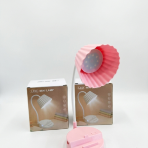 Mini lámpara LED rosa con cuello flexible y base para teléfono móvil frente a sus cajas de embalaje.