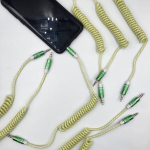 Smartphone conectado a un cable auxiliar de audio tipo rulo con terminales verdes y cable espiralado