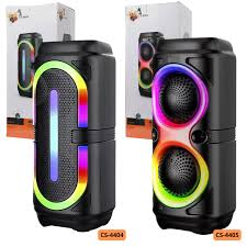 Dos parlantes Bluetooth negros de diseño cilíndrico con iluminación LED RGB vibrante, mostrados frente a sus cajas originales.